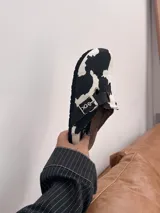 Zuecos negros con estampado de vaca en blanco y hebilla plateada.