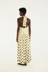 Vestido largo amarillo con estampado de lunares negros, escote halter y falda amplia.