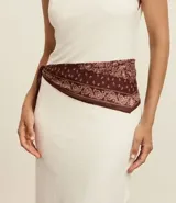 Pañuelo triangular de algodón con estampado paisley en tonos marrón oscuro y rosado claro.