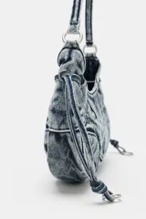 Bolso de hombro de denim con efecto acid wash, pespuntes decorativos, asa corta y tiras laterales con detalles metálicos.