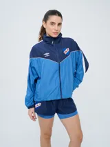 Campera deportiva Umbro del Club Nacional de Football, modelo Sky para mujer. Diseño en tonos azul marino y celeste con detalles en blanco y líneas finas rosadas, cuello alto, cierre frontal y bolsillos.