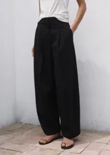 Pantalón wide leg de tiro medio color negro, con diseño largo, bolsillos laterales, bolsillos de ribete posteriores y detalle de pinzas. Cuenta con cierre oculto de botón, gancho y cremallera, e incluye forro interior.