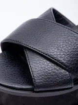 Sandalias negras de plataforma con doble cinta cruzada sobre el empeine y agarre mediante hebilla en el tobillo.