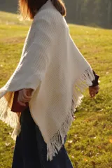 Poncho tejido en lana merino color marrón, con diseño de punto acanalado y terminación con flecos en el borde inferior. Incluye una pequeña etiqueta de cuero en la parte posterior.