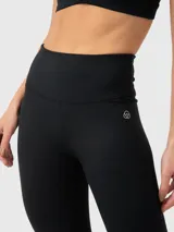 Calza deportiva de tiro alto con tecnología seamless y largo ankle. Presenta un diseño liso en color negro con logo pequeño en la cadera.
