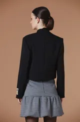 Falda corta con estampado pied de poule, diseño de corte balloon con volado en el ruedo que aporta volumen y movimiento. Presenta una silueta estructurada con detalle de tapitas decorativas en la cintura.