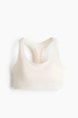 Top deportivo color beige con espalda nadadora, escote redondo y banda elástica inferior.