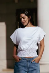 Top blanco de corte holgado con mangas cortas tipo murciélago y detalle de frunce con encaje en la cintura.