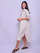 Vestido camisero largo color verde militar, confeccionado en lino, con cuello clásico, mangas largas con puños abotonados y cierre frontal con botones. Incluye un bolsillo de parche en el pecho.