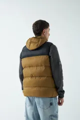 Chaleco puffer color borgoña y negro, con capucha y cuello alto.