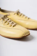Zapato acordonado de cuero color negro, de diseño minimalista con punta cuadrada y silueta moderna.