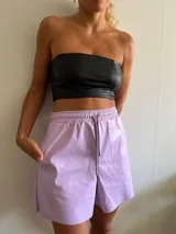 Short lila de cuero sintético con cintura elástica y cordón ajustable.