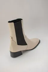Botas de cuero color beige con elásticos laterales negros, taco cuadrado y punta cuadrada.