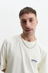 Remera de manga corta color crema, corte oversize, con cuello redondo y estampado con texto y diseño floral en el frente.