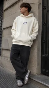 Hoodie de corte oversize color marfil, con capucha, bolsillo tipo canguro y bordado frontal en el pecho.