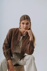 Campera bomber de cuero color marrón, con mangas abullonadas, puños elásticos y cierre frontal con botones a presión.