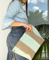 Cartera tipo sobre de cuero con diseño de rayas verticales en tonos verde menta y marrón tostado. Cuenta con detalles de borlas colgantes en los laterales.