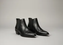 Botas bajas de cuero negro con diseño tipo chelsea, punta fina y taco cuadrado bajo.