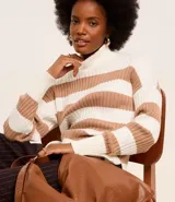 Suéter de punto pesado con cuello alto y mangas largas. Diseño a rayas horizontales en blanco y negro con textura acanalada.