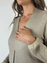 Vestido midi de punto acanalado en color gris, con escote en V, manga larga y un detalle de pliegue central en el frente que le otorga una caída fluida.