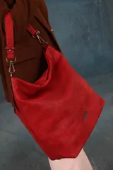 Cartera tipo bandolera de gran tamaño, confeccionada en cuero sintético con acabado desgastado. Cuenta con una asa corta fija, una correa larga regulable y extraíble, y una placa metálica con la marca en la parte frontal.