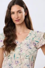 Camisa de lino estampada con diseño floral en tonos lila y verde, mangas cortas con volados y cierre frontal con botones.