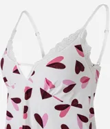 Conjunto de pijama estilo short doll compuesto por una blusa con breteles finos ajustables, escote en V con detalle de encaje, y un short corto con cintura elástica y borde de encaje. Ambas piezas presentan un estampado de corazones en tonos rosados y morados sobre fondo blanco.