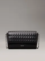 Cartera de hombro Calvin Klein negra con solapa acolchada con patrón de rombos. Posee correa de cadena metálica y logo metálico grabado en la parte frontal.
