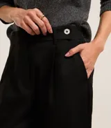 Pantalón de vestir gris con finas rayas verticales, de corte carrot, tiro alto y cierre frontal con botón.