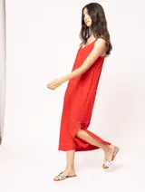 Vestido largo color crudo de lino, con silueta recta, escote en V, breteles anchos, detalle de elástico en la espalda y tajos laterales.