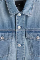 Campera de denim celeste con cuello clásico, cierre frontal con botones metálicos, bolsillos con solapa en el pecho y bolsillos laterales. Corte holgado.