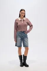 Sweater de tejido de punto con trenzas, color malva/rosado, de corte cropped y manga larga. Presenta cuello polo con solapas en color crema y cierre frontal de botones.