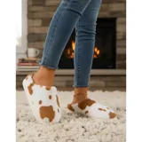 Pantuflas sin talón confeccionadas en algodón afelpado y piel sintética, con divertido estampado de manchas de vaca en tonos blanco y marrón, y suela de PVC.