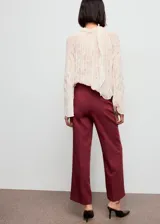 Pantalón de vestir color bordó, de tiro alto y diseño recto, con bolsillos laterales y cierre oculto con botón, gancho y cremallera.