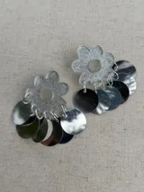 Aros dorados con forma de flor brillante en la parte superior y múltiples discos metálicos colgantes.