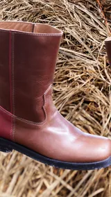 Botas cortas de cuero color marrón con detalle de costuras en la parte delantera y trasera. La parte trasera es de cuero color bordó.