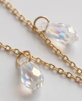 Collar de cadena eslabonada en acero con baño de oro, con múltiples dijes colgantes en forma de gota de cristal facetado tornasolado.