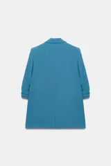 Blazer negro de cuello con solapas de muesca y hombreras, con mangas tres cuartos drapeadas, bolsillos de vivo simulados y cierre frontal con un botón dorado. Forro interior a tono.