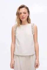 Musculosa negra con cuello redondo y detalles de volados en los hombros, confeccionada en una mezcla de algodón y Tencel.