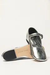 Zapato plano estilo Mary Jane de cuero negro, con punta fina y tira ajustable con hebilla sobre el empeine.