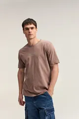 Remera de algodón color marrón con efecto gastado, de manga corta, cuello redondo y estampa tipográfica sutil al frente.