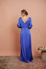 Vestido largo de satén color azul, con escote en V cruzado, mangas tres cuartos con detalles de lazos en los puños y falda larga con tajo frontal.