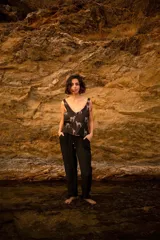 Pantalón negro de algodón con textura y ajuste holgado que se estrecha hacia los tobillos. Presenta tiras para ajustar la cintura, con terminaciones de cobre.