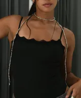 Collar tipo choker y tiras colgantes, compuesto por pequeñas cuentas plateadas. El diseño incluye un choker ajustado al cuello y dos tiras largas que caen sobre el pecho y los hombros, sujetas a una prenda negra con un broche metálico central.