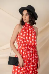 Vestido midi de gasa con seda, color rojo con lunares blancos, cuello halter, cintura elastizada con lazo y volado en el ruedo.