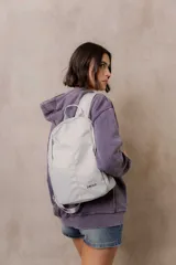 Mochila compacta de color beige, con compartimento principal con cierre, bolsillos laterales y bolsillo frontal con cierre oculto. Cuenta con correas regulables y acolchonadas y asa superior.