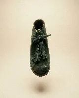 Bota de caña media confeccionada en cuero gamuzado color marrón chocolate. Presenta un diseño de estilo mocasín con cordones frontales decorados con borlas desmontables y suela plana de goma resistente.