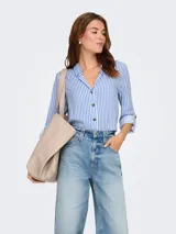 Camisa de corte suelto y textura fluida, con estampado de rayas verticales en azul y blanco. Presenta cuello camisero, cierre frontal de botones y mangas largas con opción de enrollado.