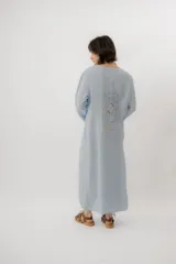 Vestido largo de lino color tostado, de manga larga, con escote redondo y diseño amplio y fresco. Cuenta con un delicado bordado en la espalda con motivos marinos y la frase "no se lo digas".
