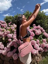 Bandolera de diseño moderno y funcional, confeccionada en nylon color marrón claro. Cuenta con múltiples compartimentos con cierre metálico, herrajes plateados y una correa ancha ajustable con detalle de marca.